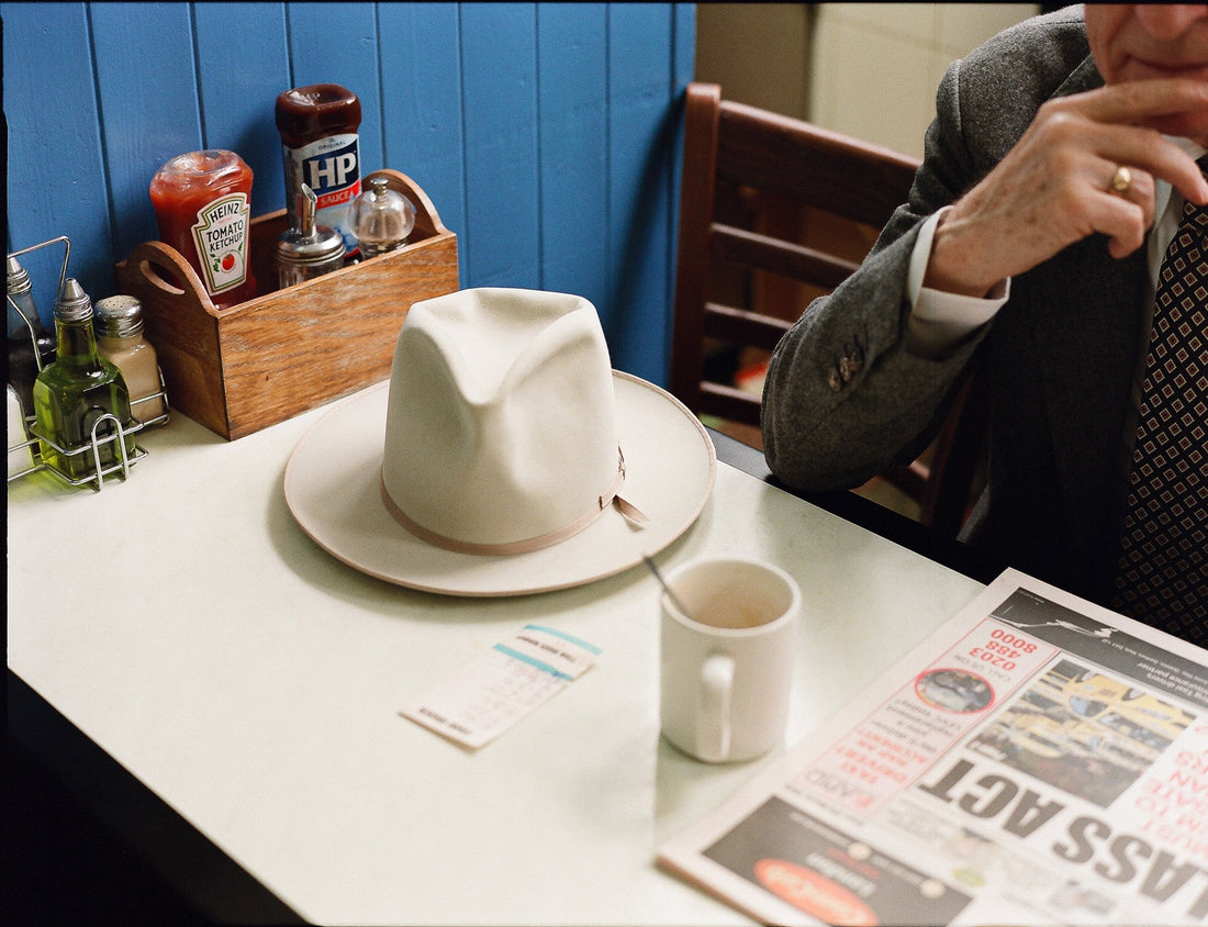 Wellema x Bryceland's Hat sitting table at the Astral acfe by a cup of tea and a news papars