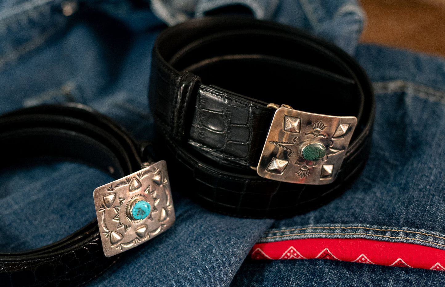Red rabbit Trading Co. And Bryceland’s & Co. Collaboration silver and turquoise belt buckle inspired by Oppenheimer film staring cillian Murphy. Resting on denim jeans. Alligator skin black belt.