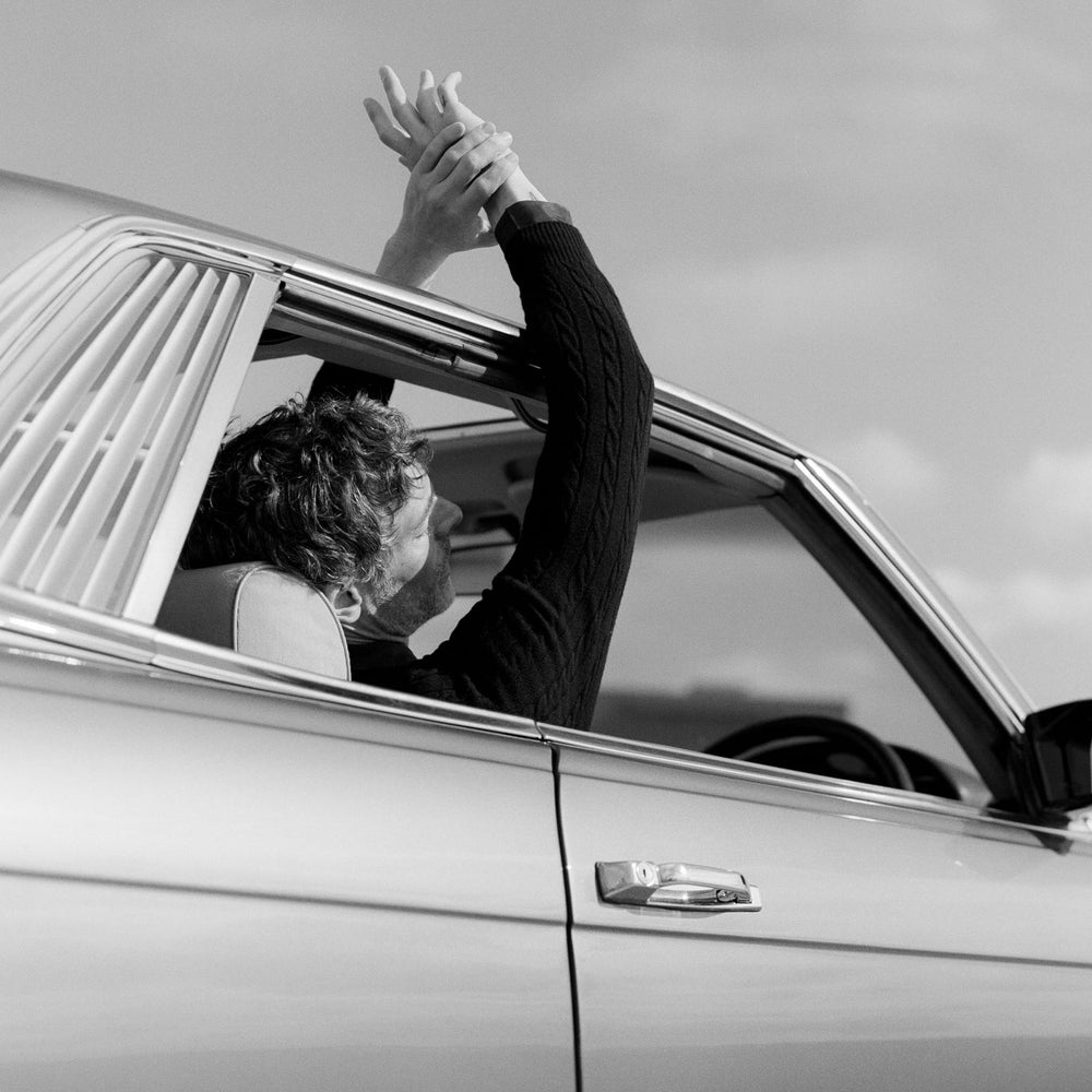 Black and White image of Richard Biedul relaxing in a classic car