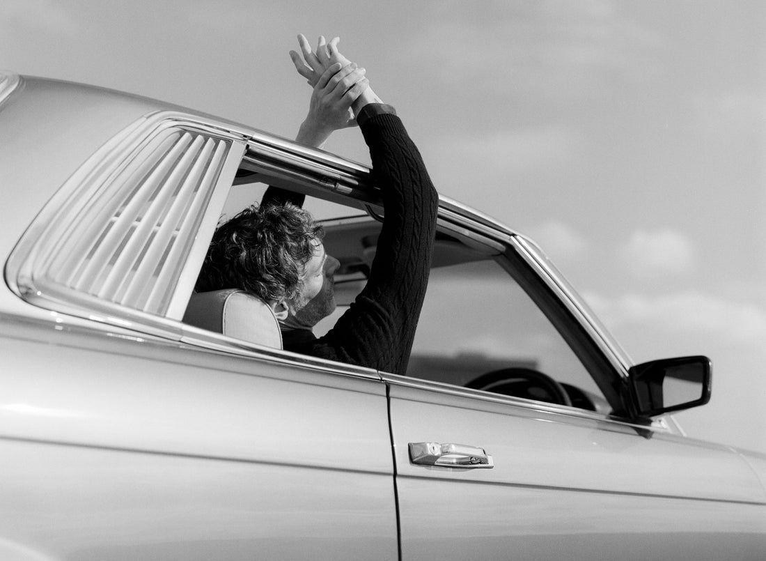 Black and White image of Richard Biedul relaxing in a classic car